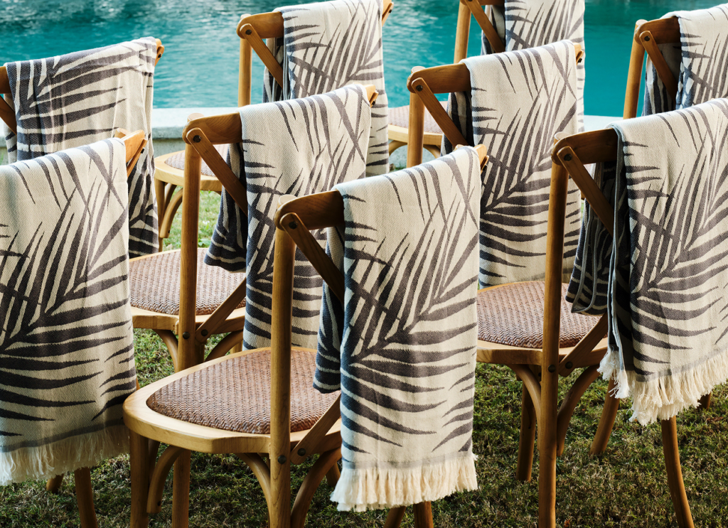 Elegant towels draped over the back of wooden chairs, perfect as guest gifts for weddings or special events.