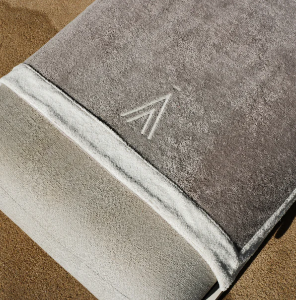 A luxurious beige and brown beach towel, neatly folded, part of a curated Sun of a Beach welcome gift.
